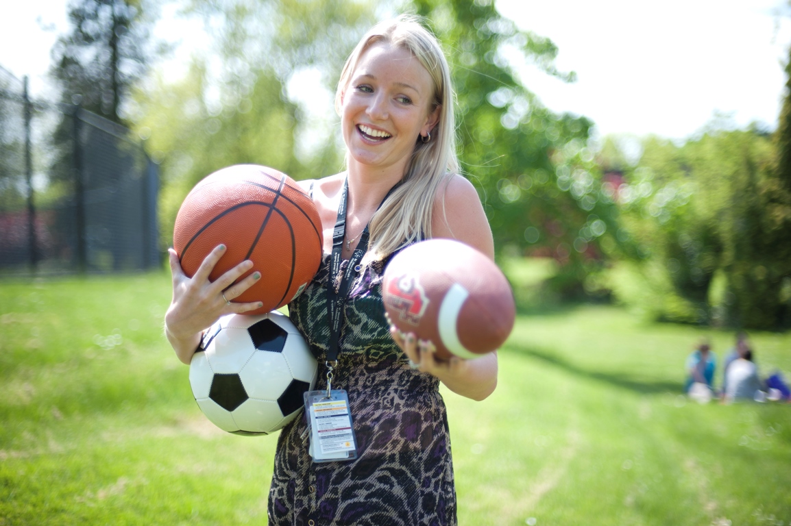 Woman holding a football, soccer ball and basketball